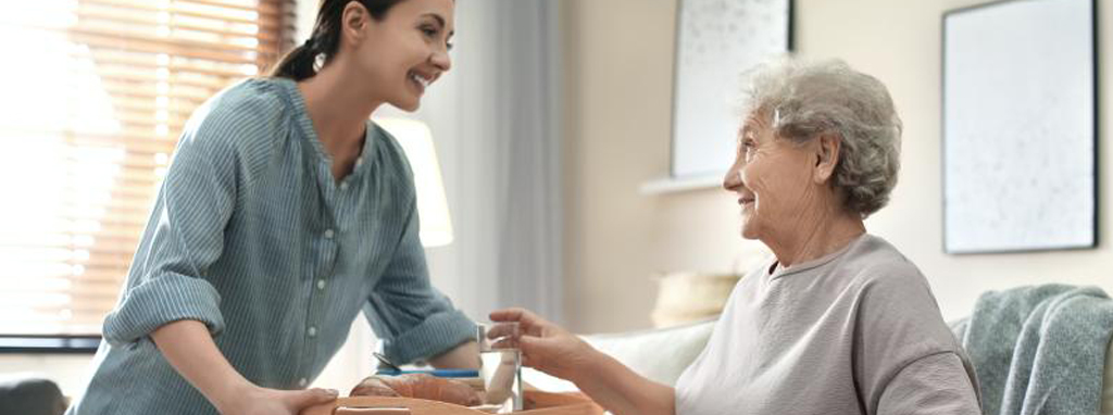 Caretaker giving water to a patient in their home