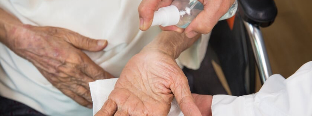 Home care specialist sanitizing elders hands