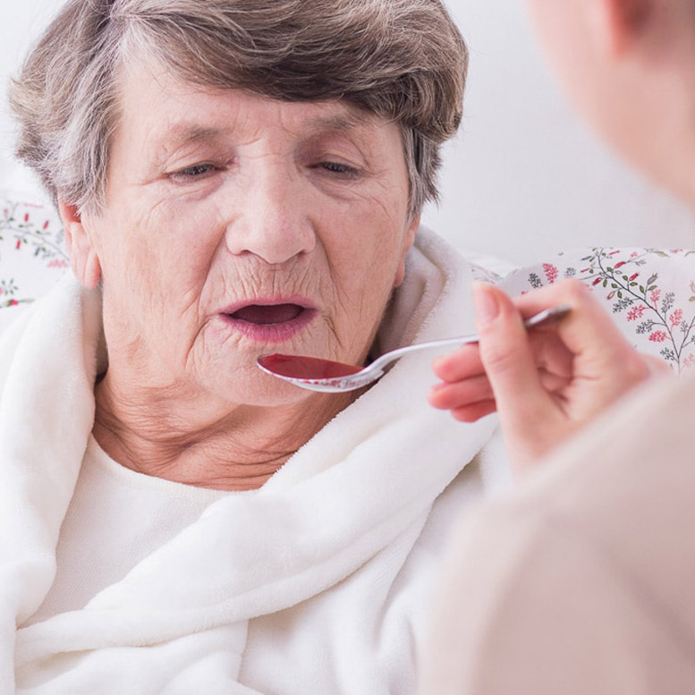 Home health aide feeding elderly woman