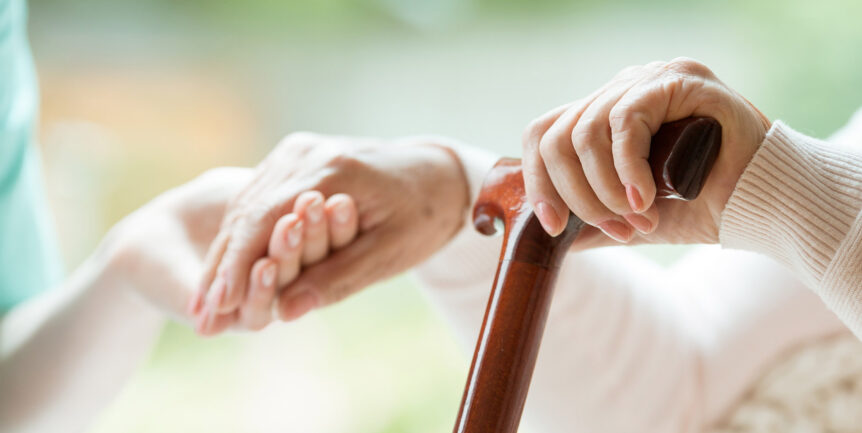 Home care assistant helping an elderly up