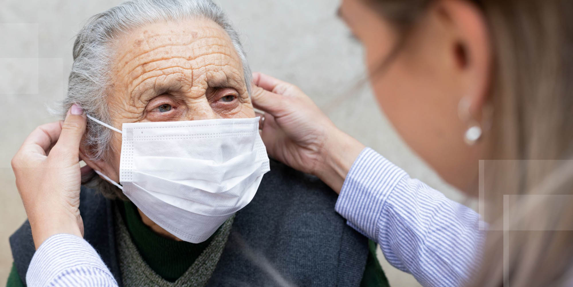 home care assistant practicing safety putting mask on elderly woman